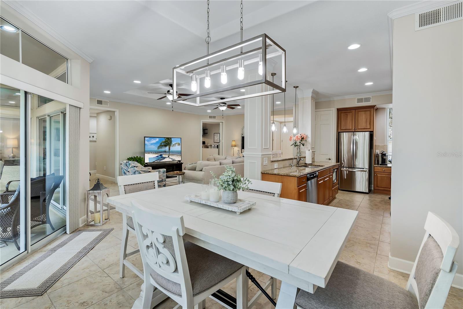 Open-plan dining room with a large white table, kitchen island and stainless steel appliances.