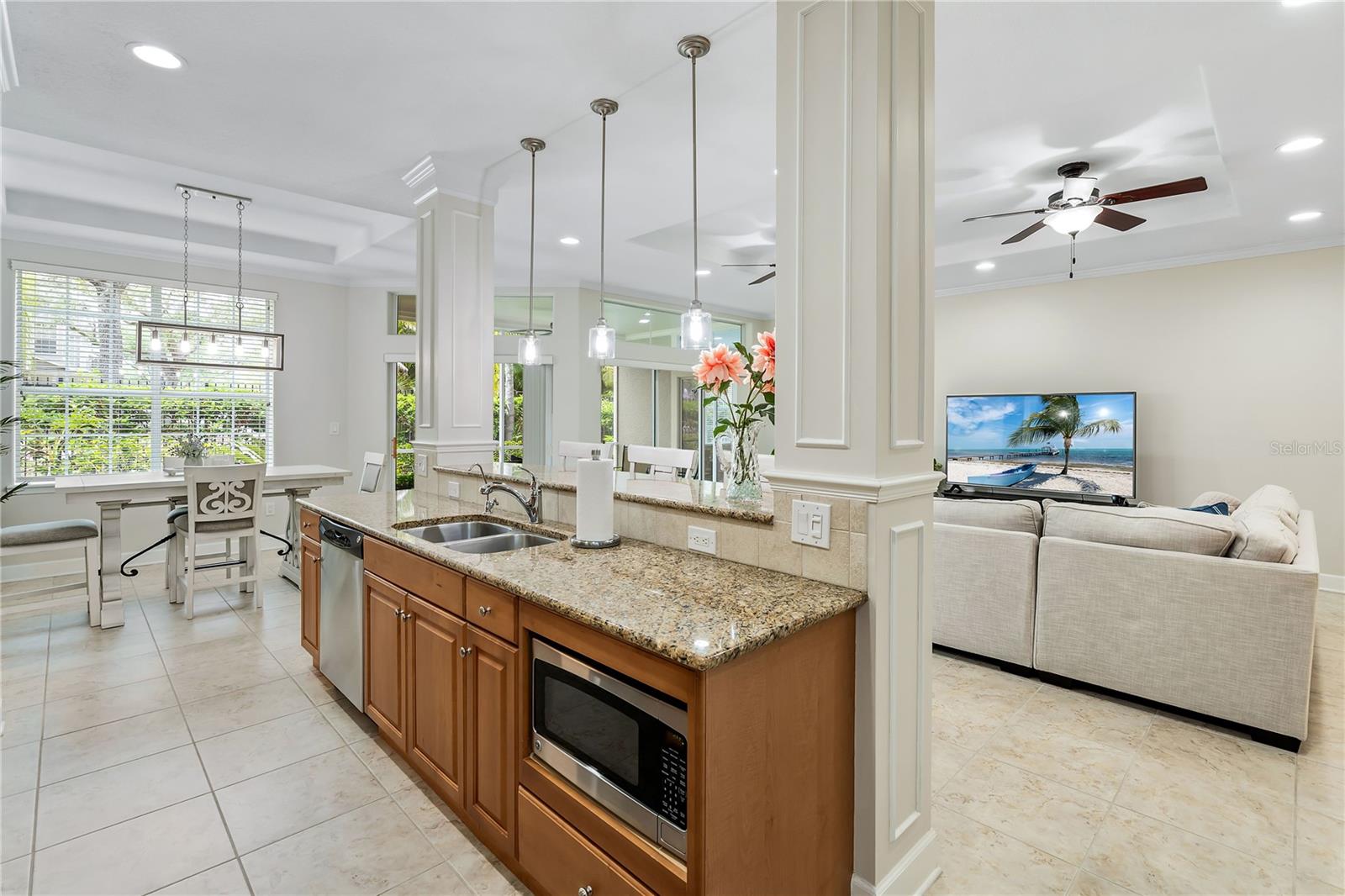 Open-plan kitchen with granite island and wood cabinetry adjoining a dining area and furnished living room.