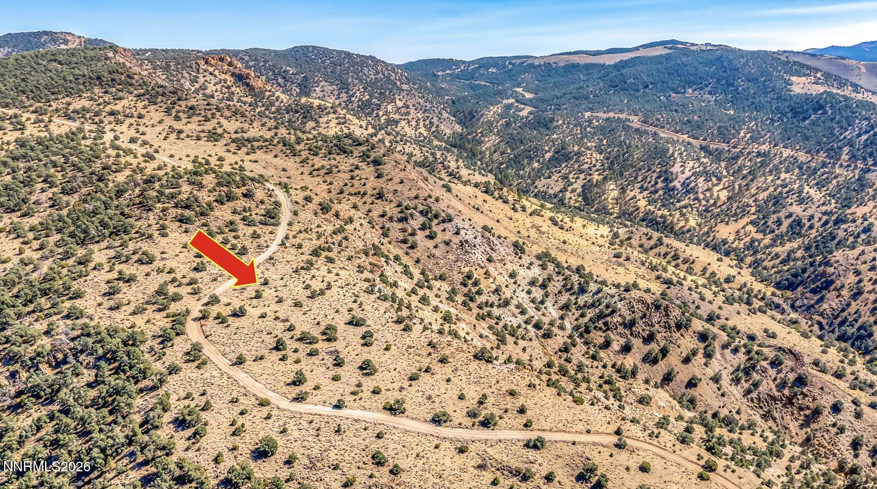 Aerial view of the Geiger Grade Road parcel, marked by a red arrow beside a winding dirt road.