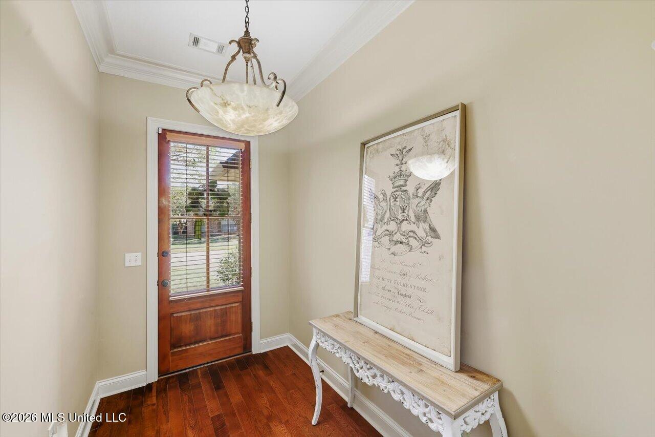 Entry foyer with a wood-and-glass door, dark hardwood floor, and ornate console table.