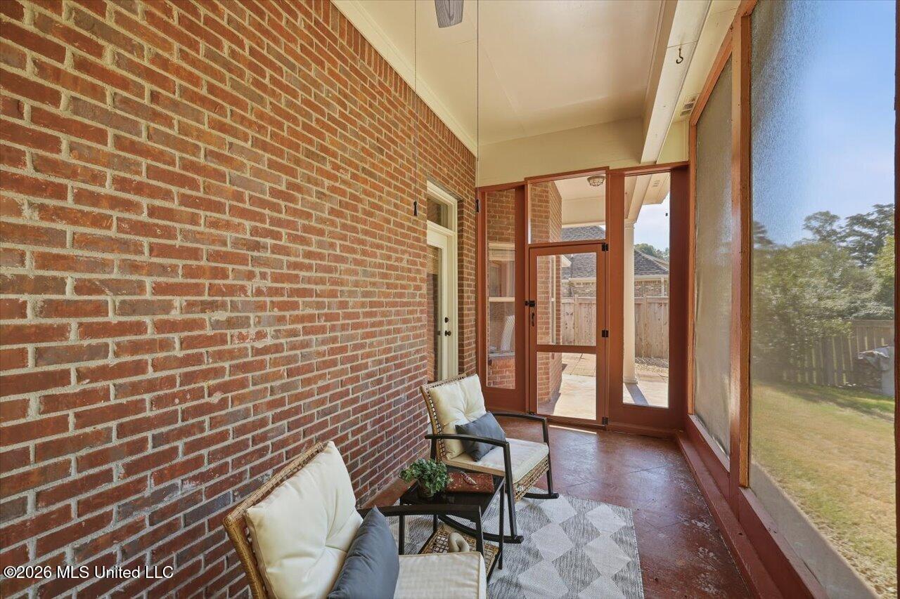 Screened porch with brick walls, wicker seating, and a view of the yard.