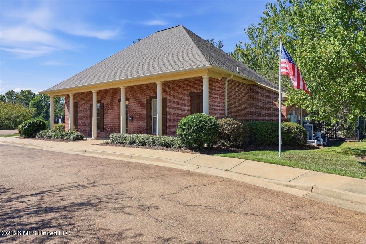 Brick building with a columned entrance, landscaped frontage, and an American flag.