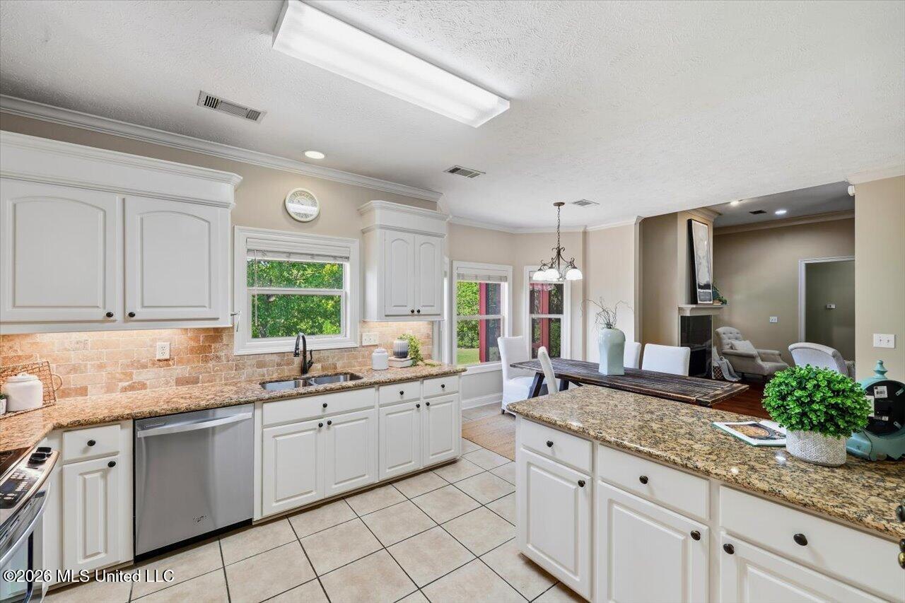 Kitchen with white cabinets, granite counters, and a breakfast bar overlooking the dining area.