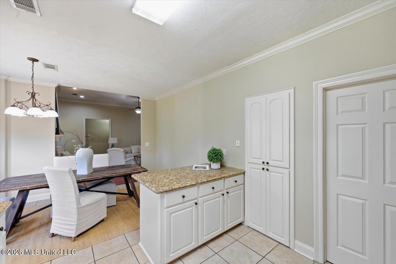 Kitchen with granite island and white cabinets opening to a dining area.