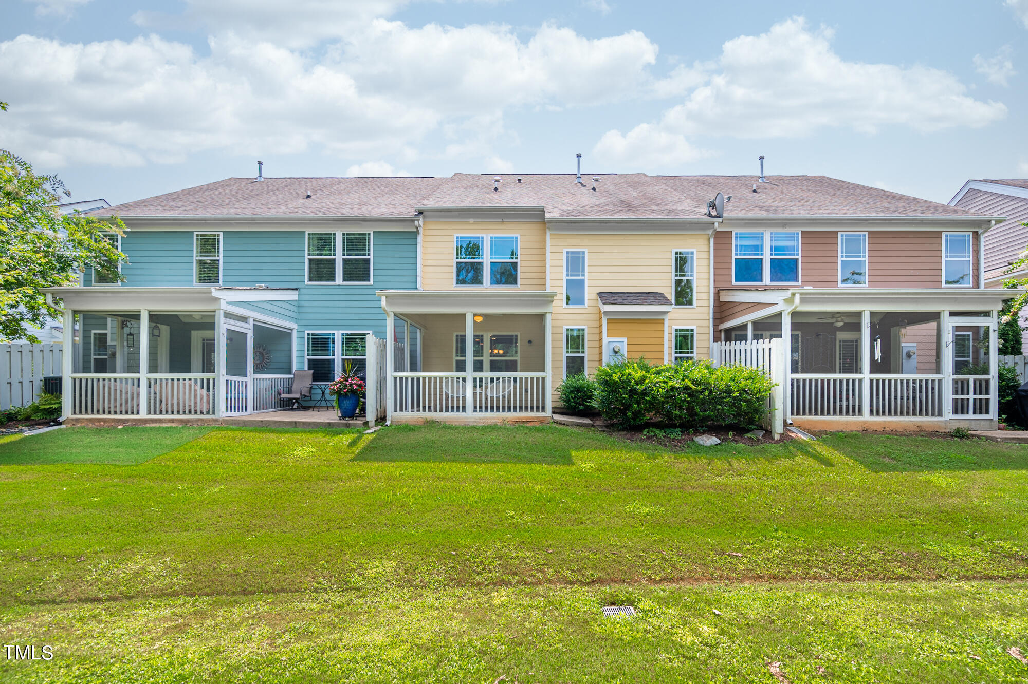 Rear of attached homes with screened porches and a broad green lawn.