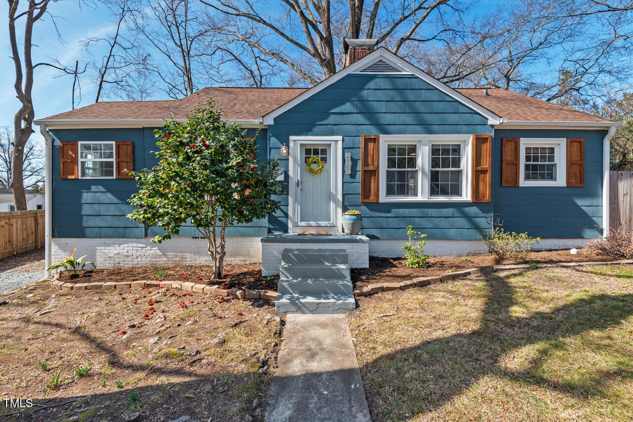 Blue single-story house with white trim, brown shutters, and a central front walkway.