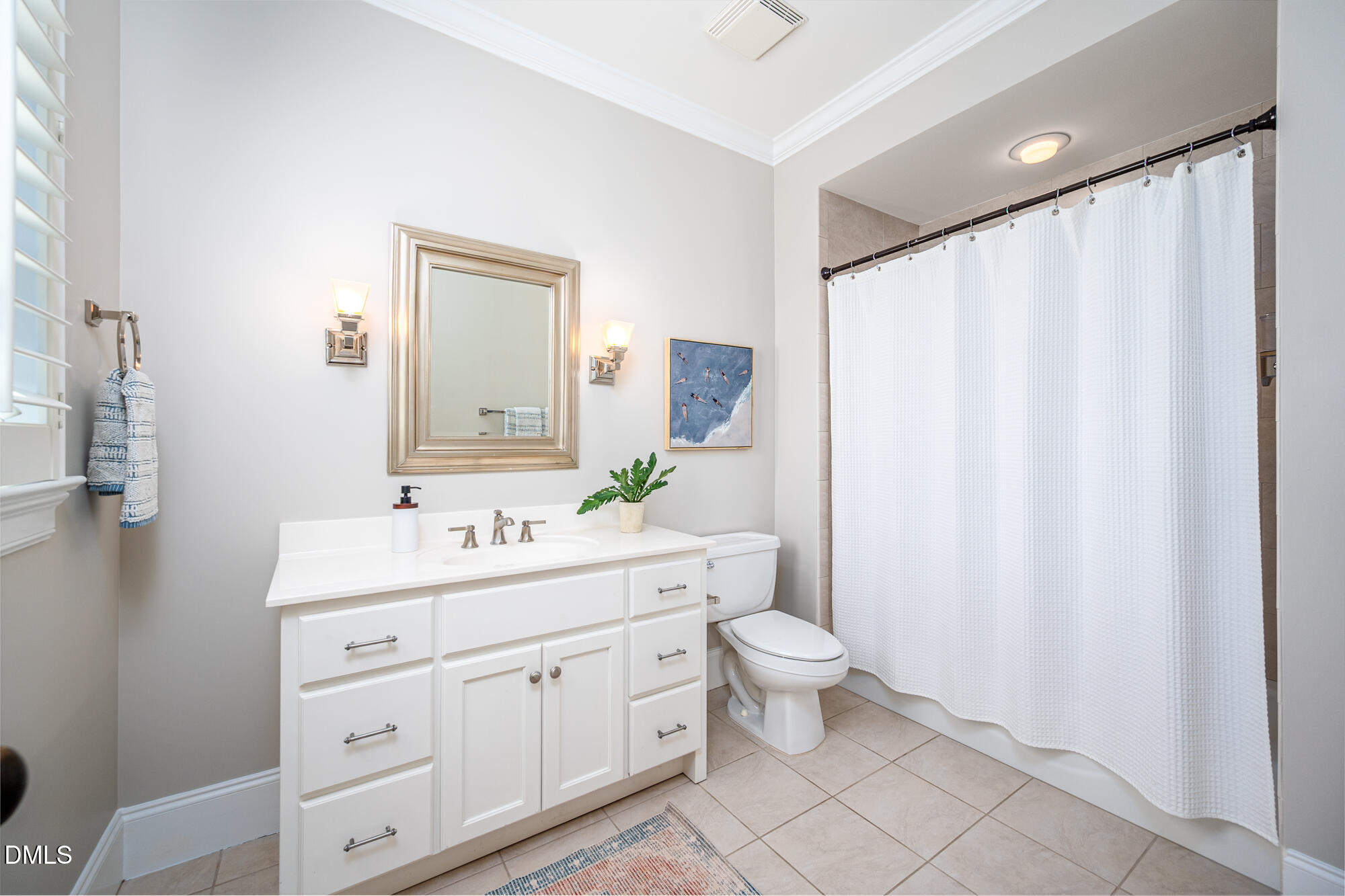 Bathroom with a white vanity, framed mirror, and shower curtain beside the toilet.