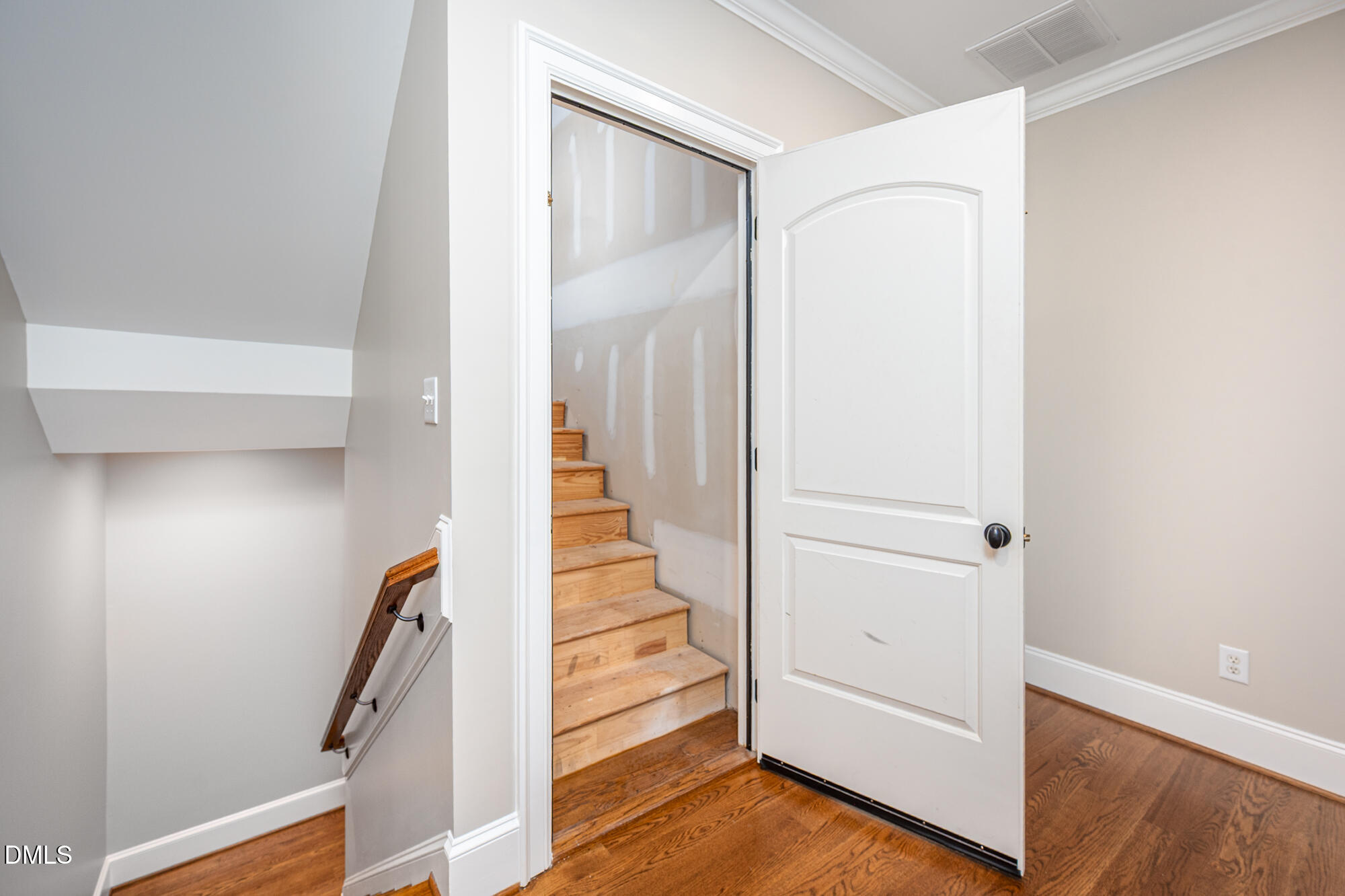 Open door reveals a staircase with unfinished drywall and bare wooden steps.