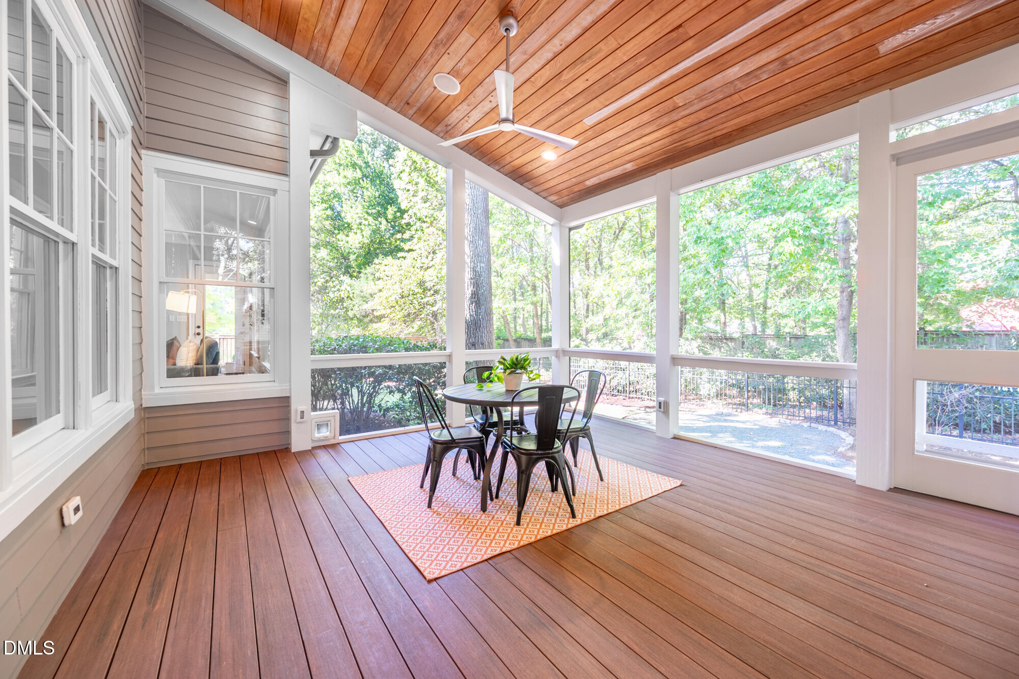 Screened porch with wood-plank ceiling, dining set, and leafy views.