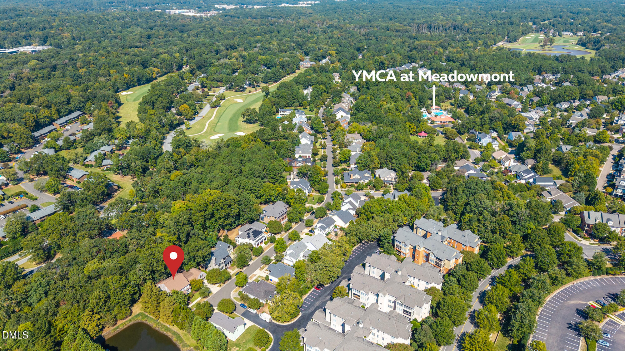 Aerial view of 1216 Pinehurst Drive among wooded homes, with a nearby golf course and YMCA at Meadowmont.