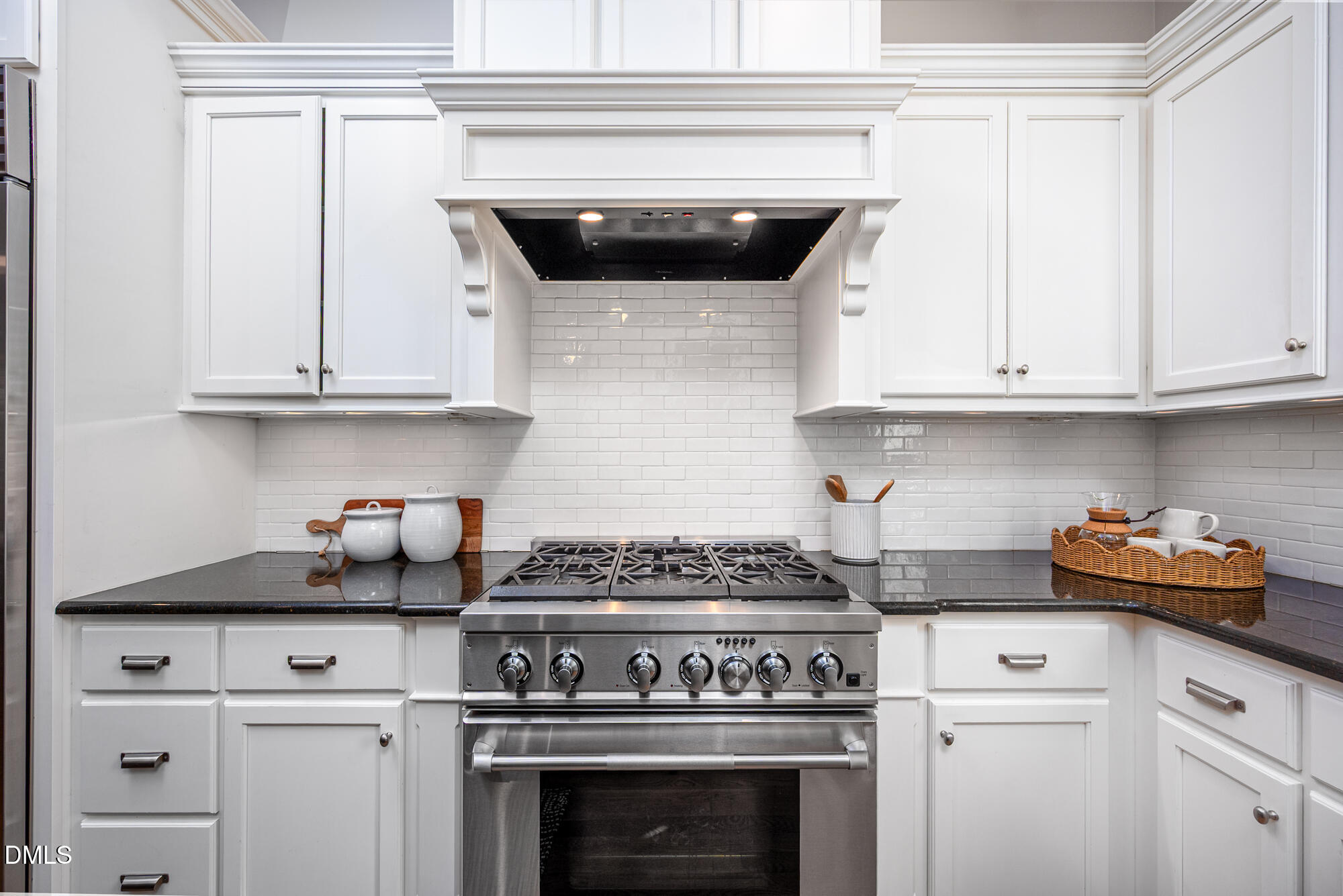 Kitchen with a stainless-steel gas range, white cabinetry, subway-tile backsplash, and dark countertops.