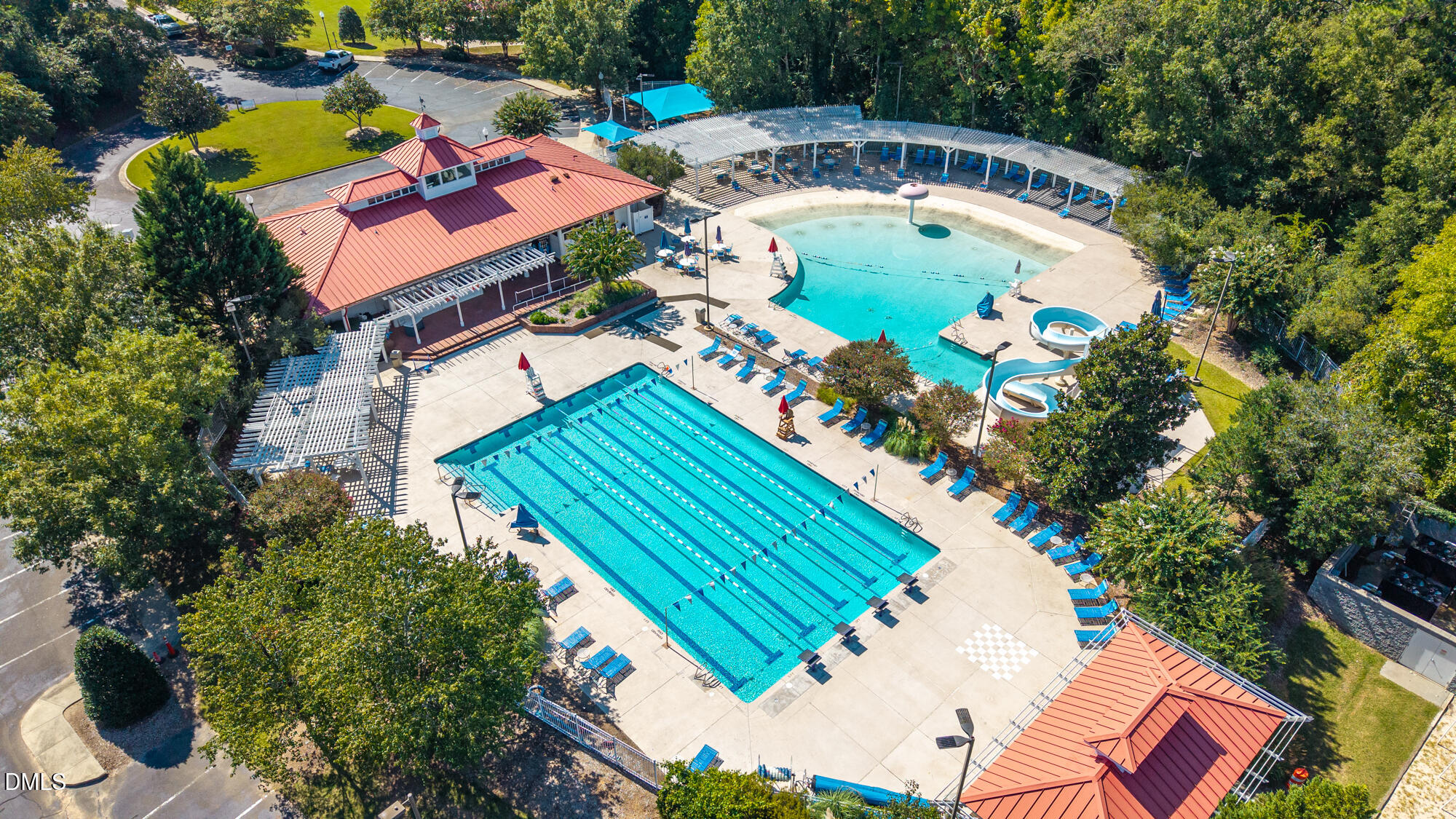 Aerial view of a lap pool and leisure pool beside a red-roofed pavilion.