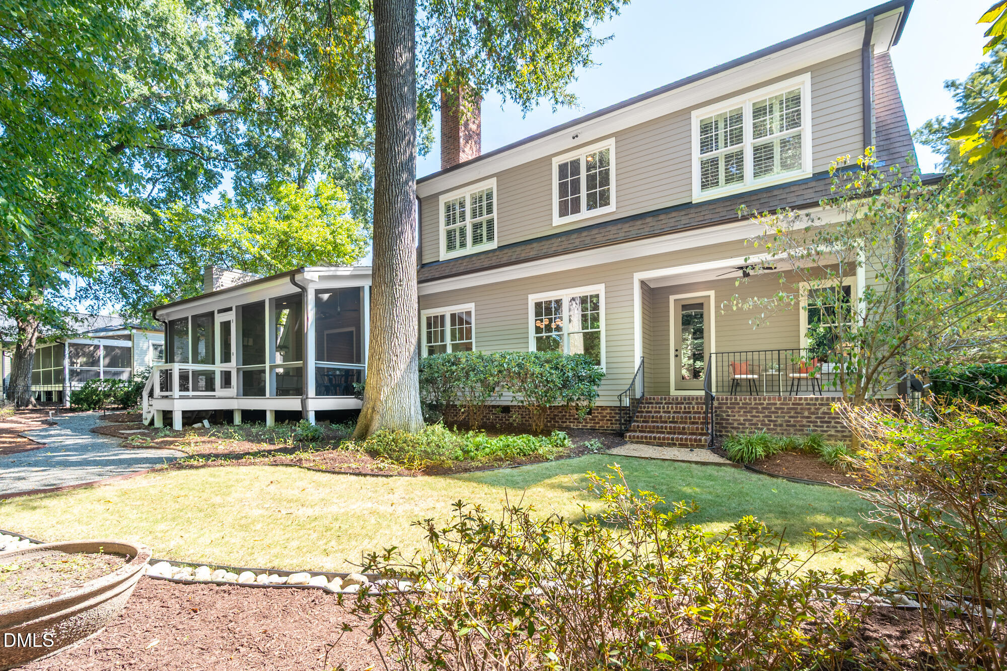 Two-story taupe house with a screened porch, brick steps, and mature trees in the yard.