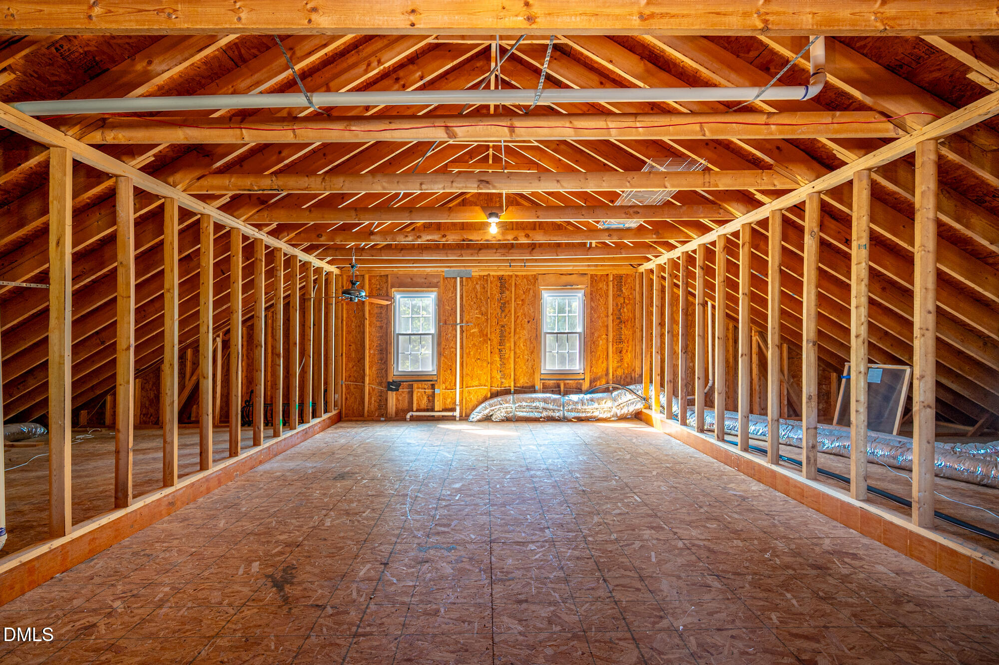 Unfinished attic with exposed timber framing, two windows, and visible HVAC ductwork.