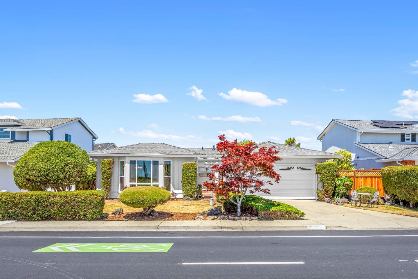 Single-story home with a two-car garage, landscaped front yard, and red-leaf tree.
