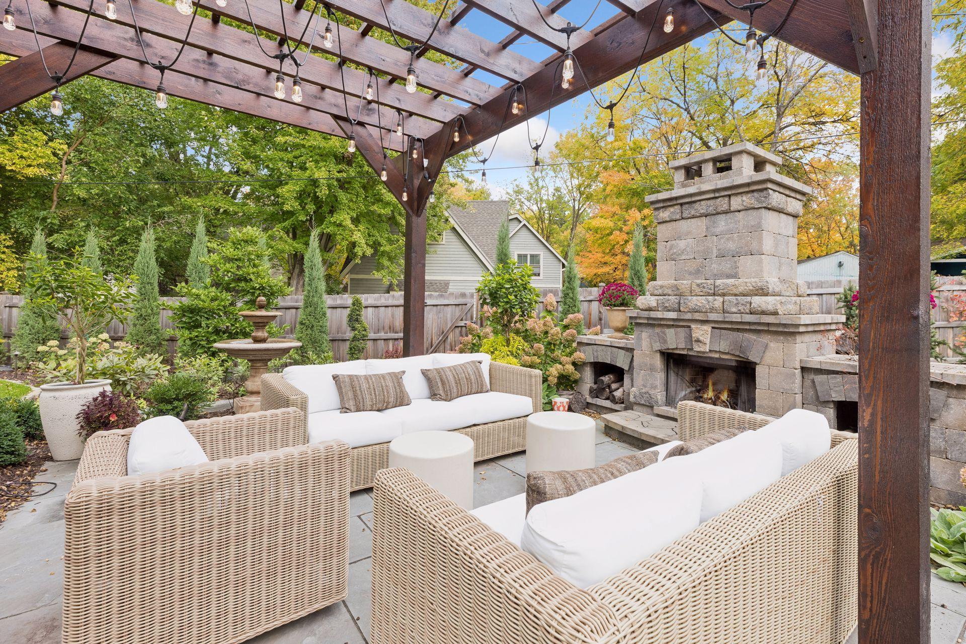 Outdoor patio with pergola, wicker seating, and a large stone fireplace