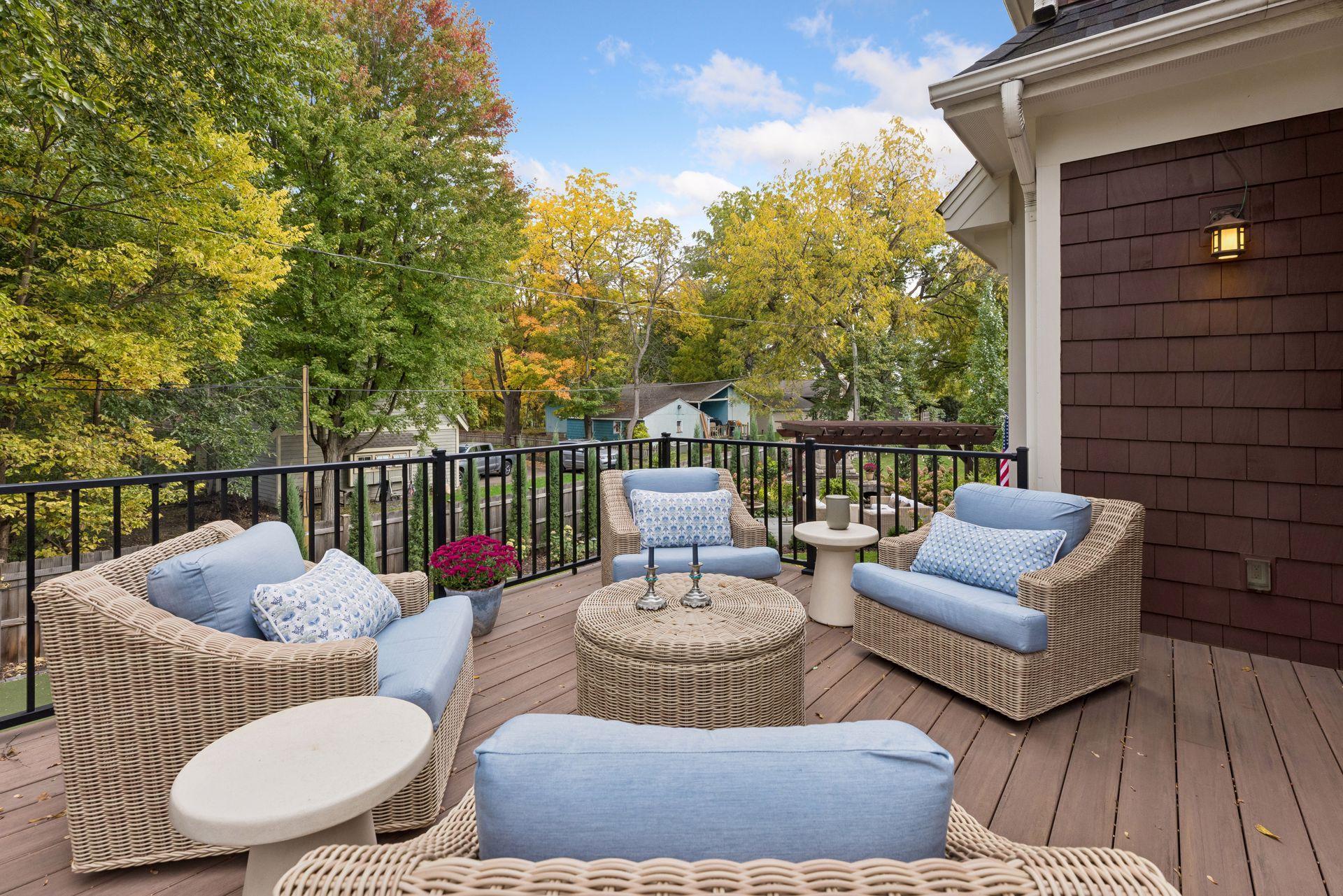 Furnished deck with wicker seating and blue cushions overlooking leafy yards.