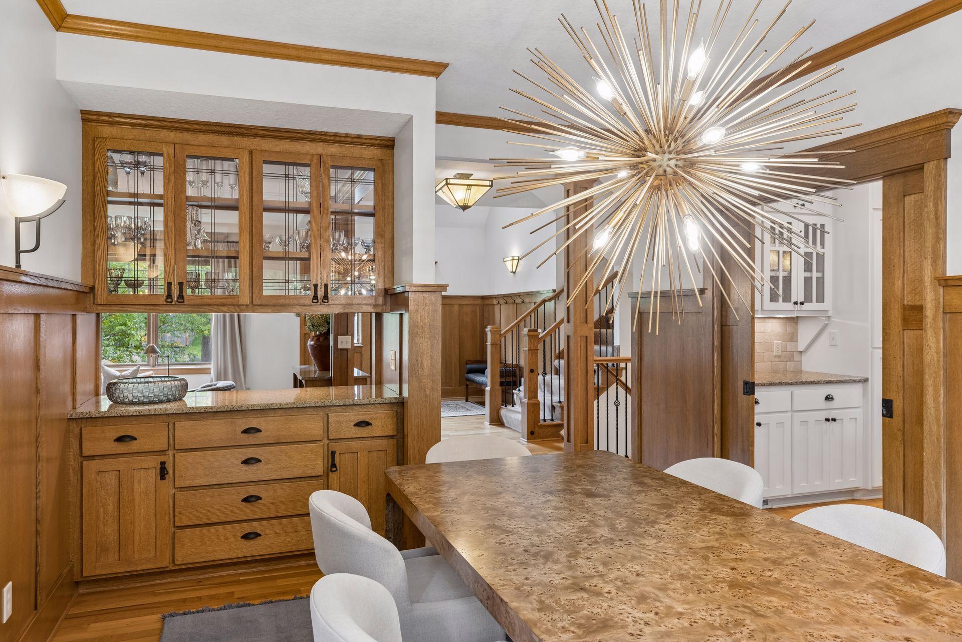 Dining room with a stone-top table, oak cabinetry, and a dramatic starburst chandelier.
