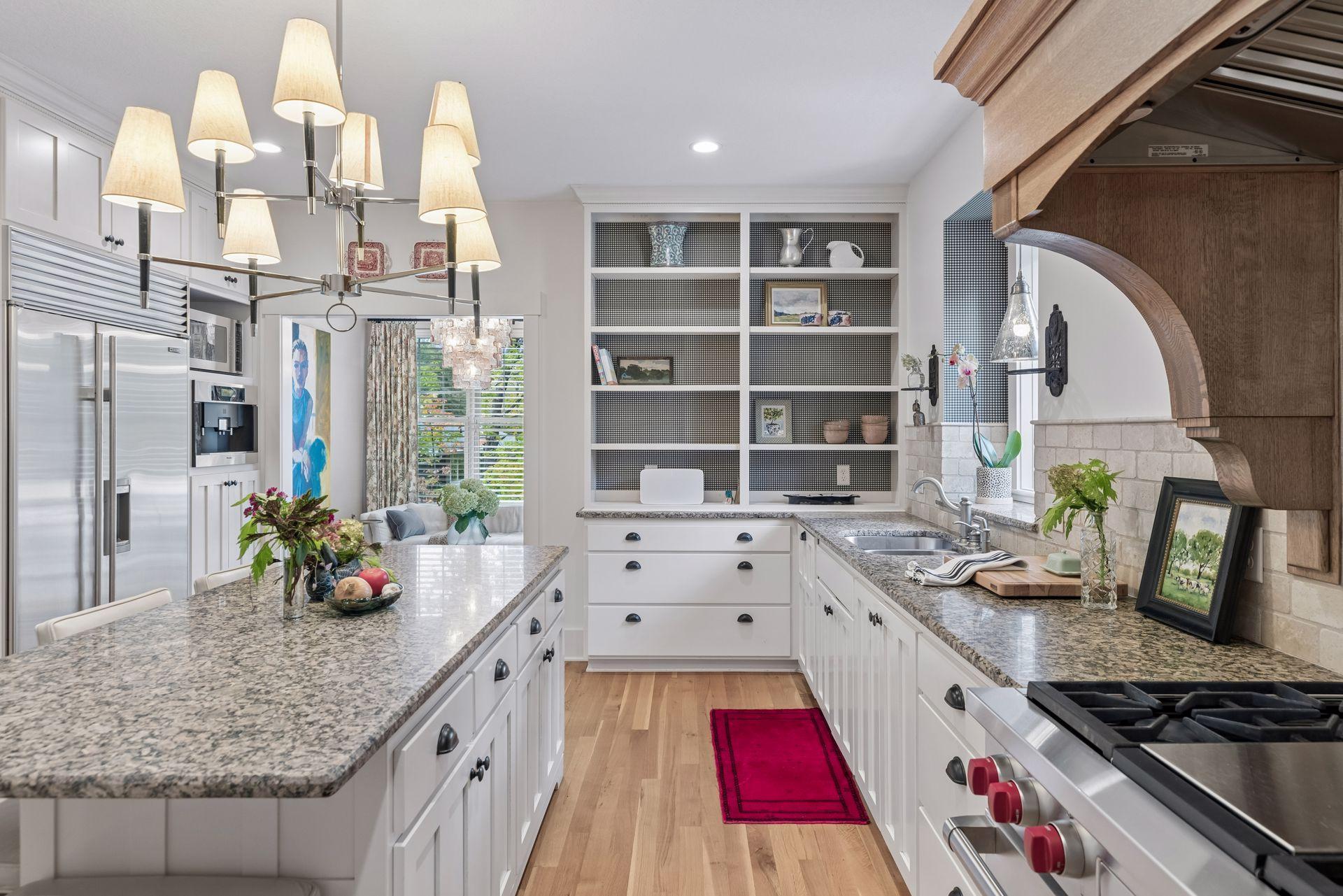 Bright kitchen with white cabinetry, granite counters, stainless steel appliances, and a wood-trimmed range hood.