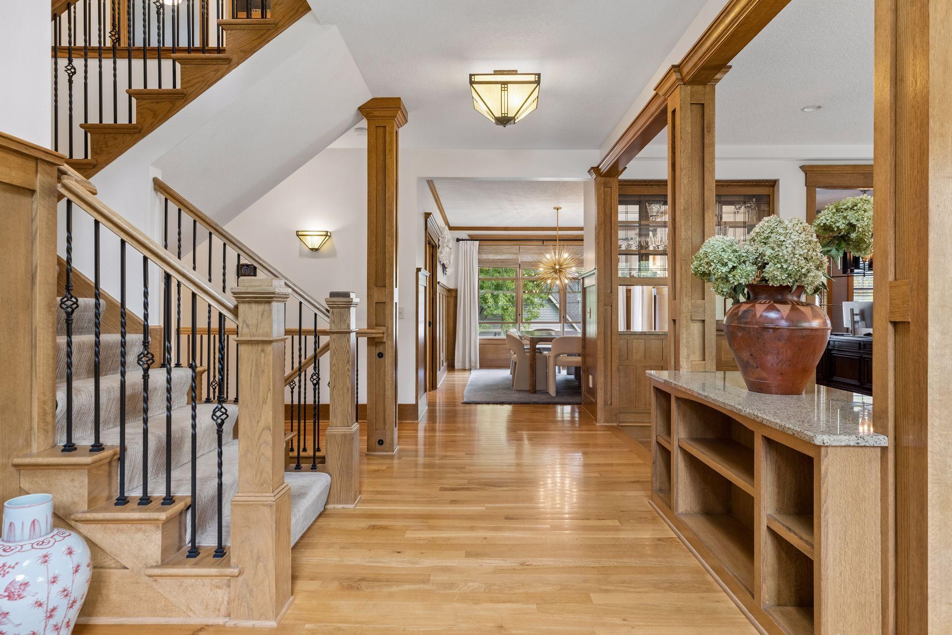 Foyer with a sweeping staircase, iron balusters, rich wood trim and a dining area beyond.