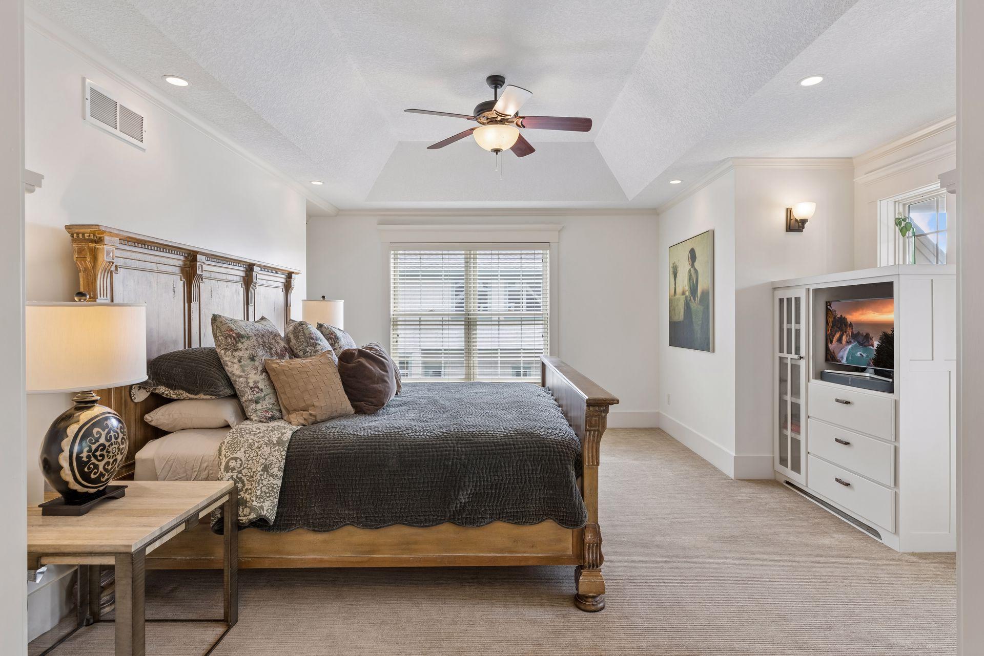 Bedroom with a carved wooden bed, tray ceiling, and built-in television cabinetry.