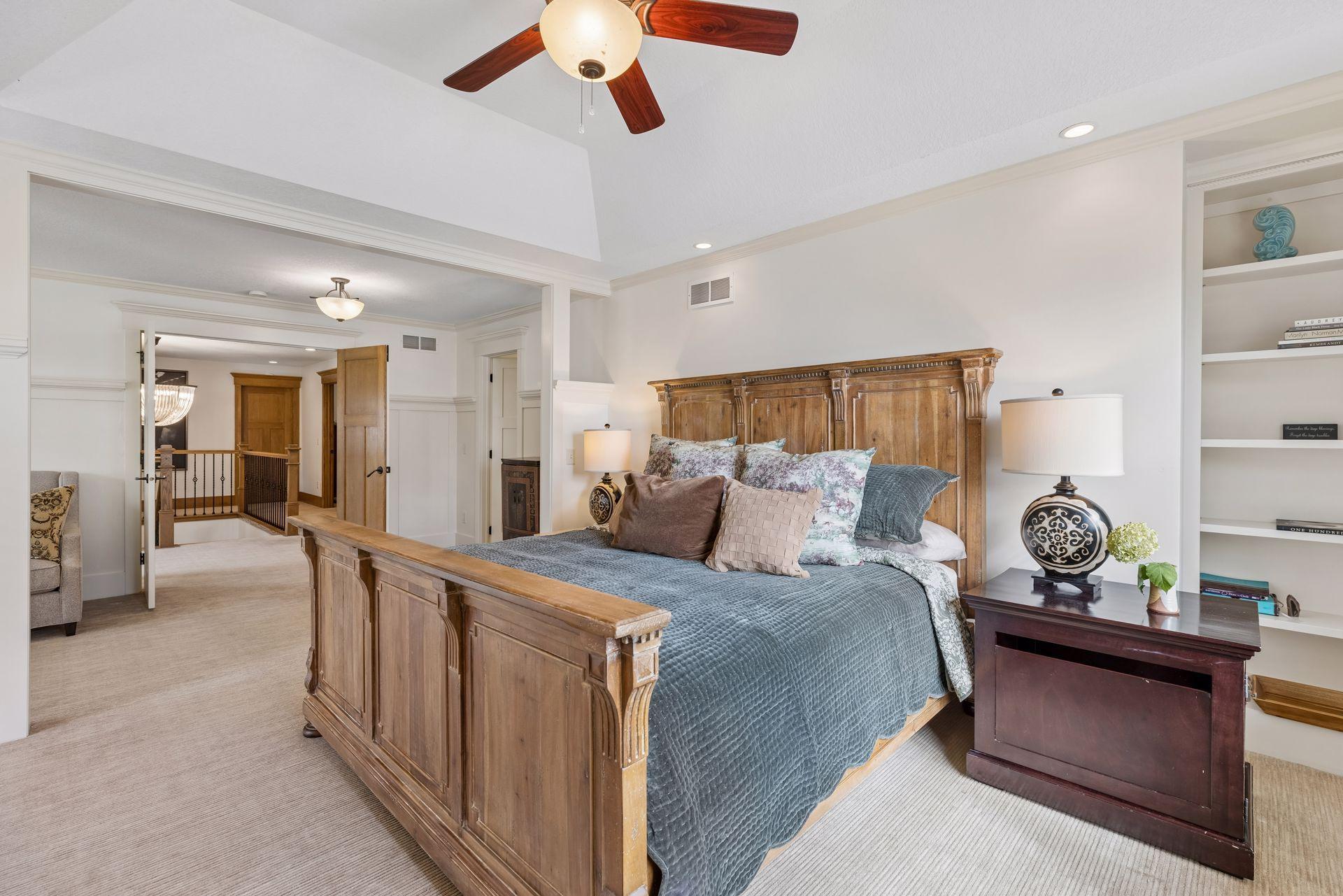 Furnished bedroom with a carved wooden bed, blue-gray bedding, and built-in shelves.