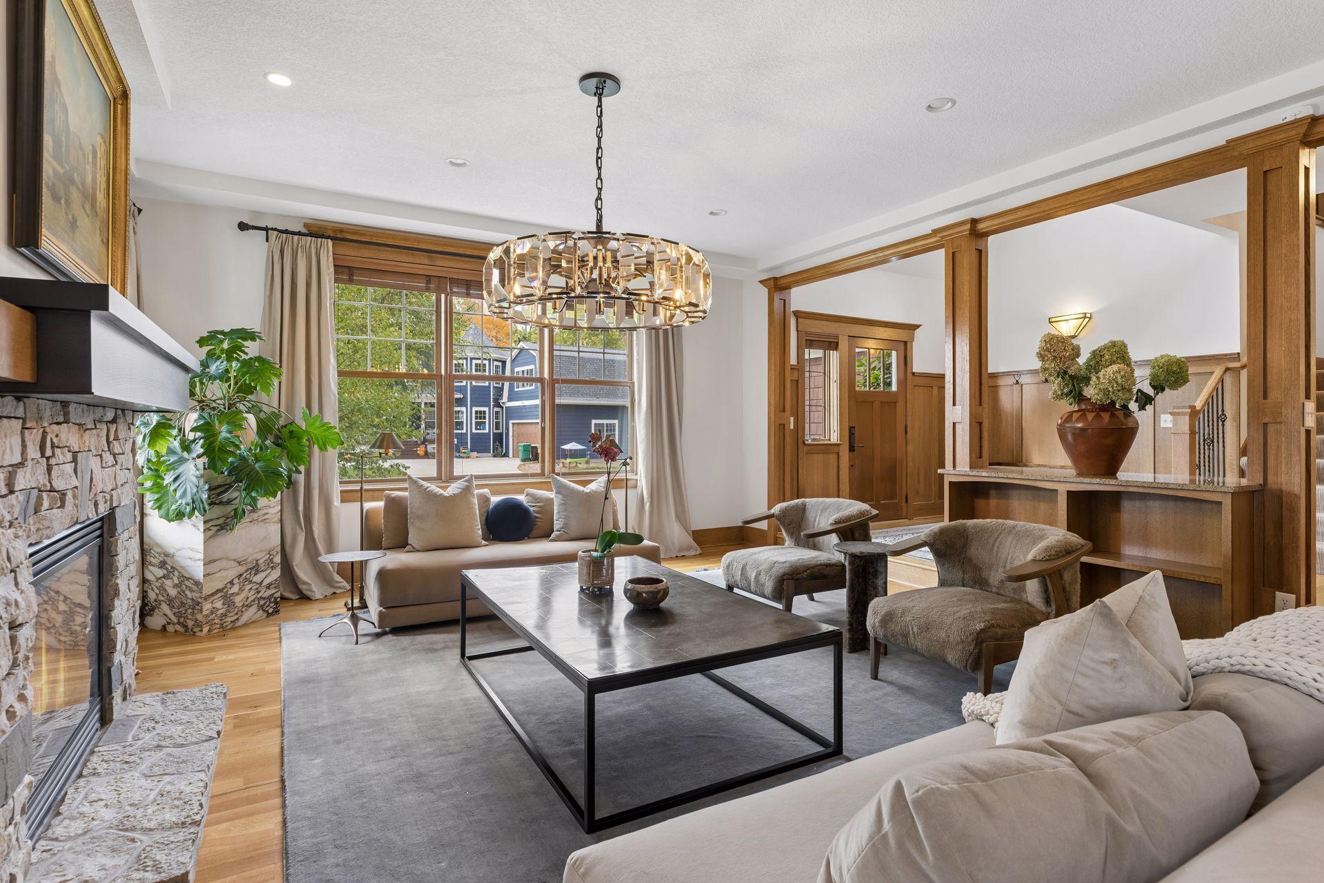Living room with a stone fireplace, wood trim, and a large chandelier above the seating area.