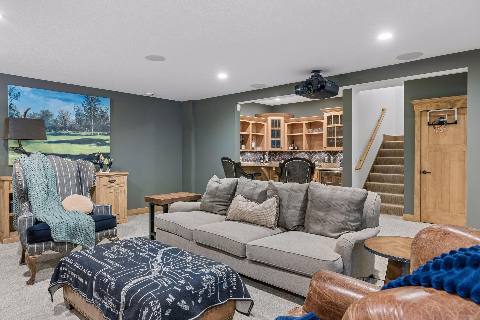 Furnished basement family room with a ceiling projector, wet bar, and basketball hoop.