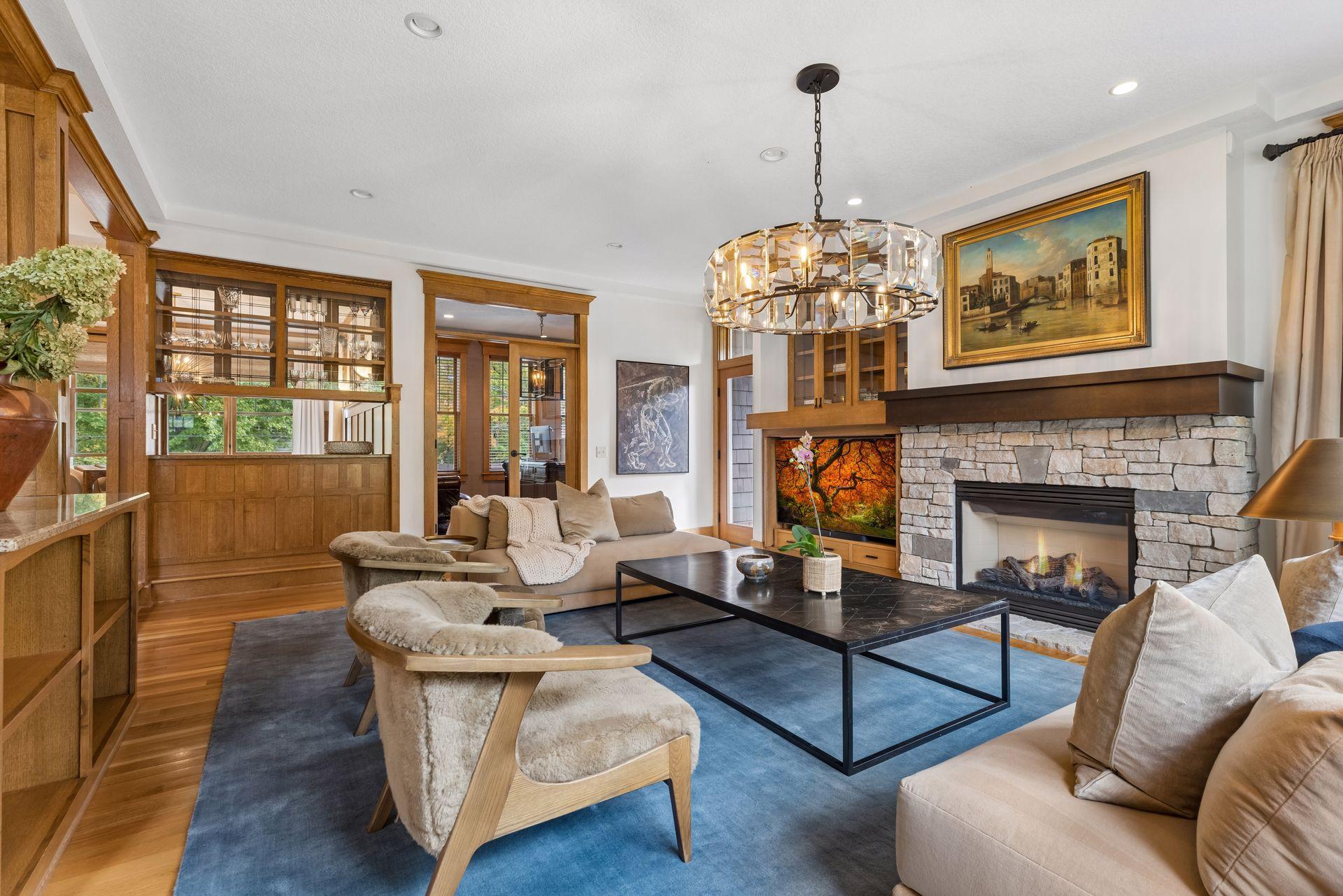 Living room with a stone fireplace, crystal chandelier, and built-in wood cabinetry.