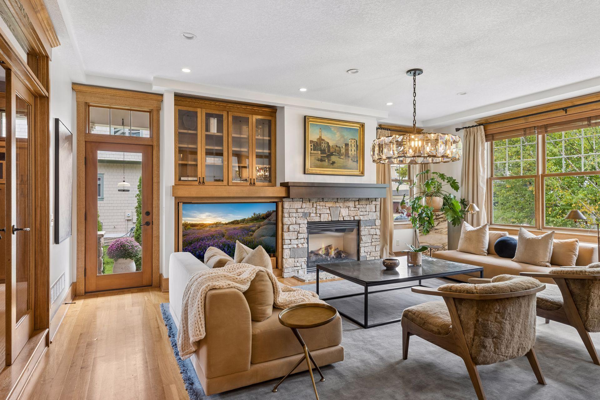 Staged living room with a stone fireplace, built-in wood cabinetry, and large windows.