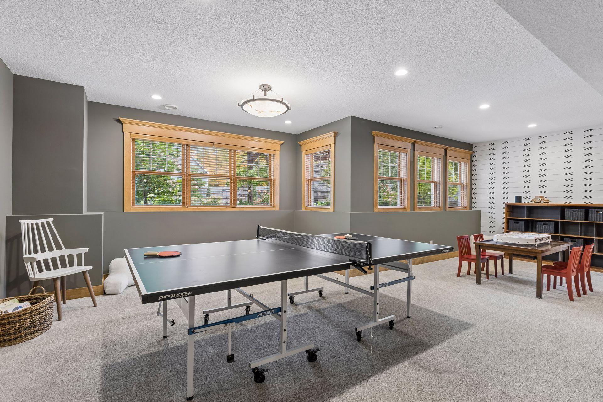 Recreation room with a ping-pong table, wood-trimmed windows, and a patterned accent wall.