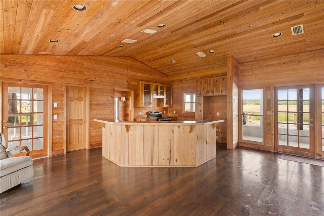 Wood-paneled kitchen with a large central island and glass doors opening outdoors.