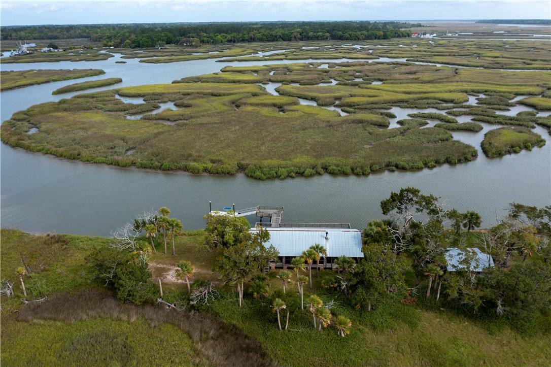 Aerial view of a house and dock beside tidal creeks and expansive marshland.