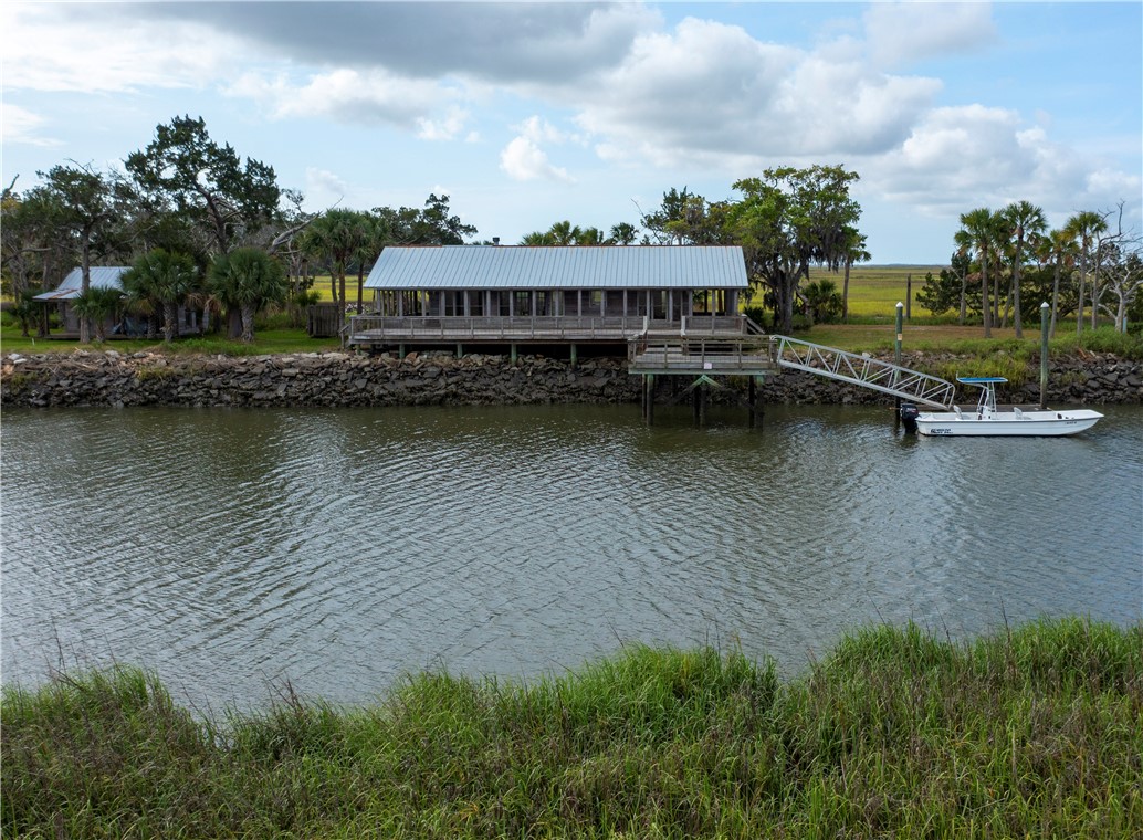 Waterfront house with a dock and boat beside marshland.