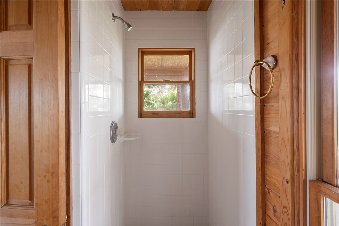 Tiled shower stall with a wood-framed window and warm wooden trim.