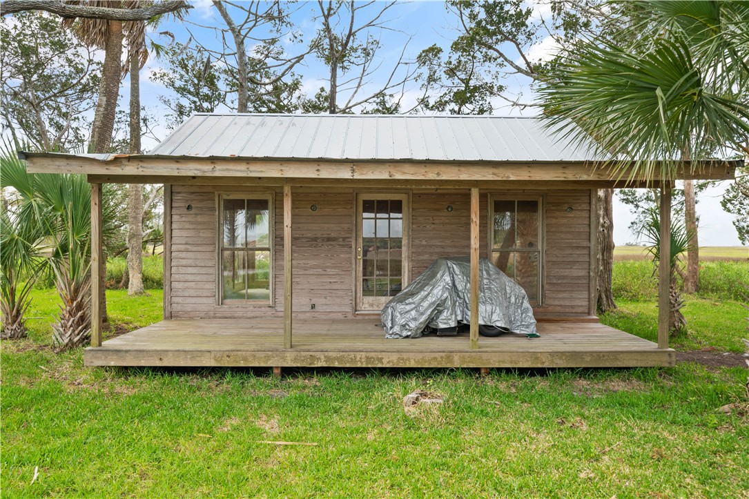 Small wood cabin with a metal roof, wide covered porch, and palm trees