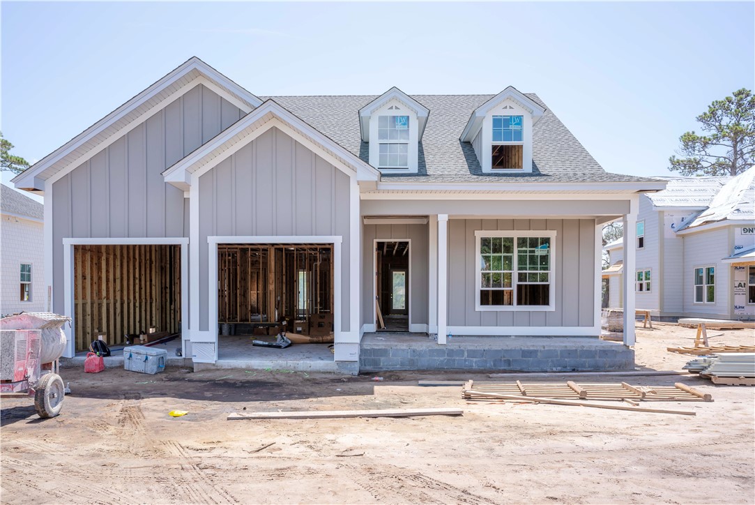 Gray two-story home under construction with two open garage bays and a covered entry.