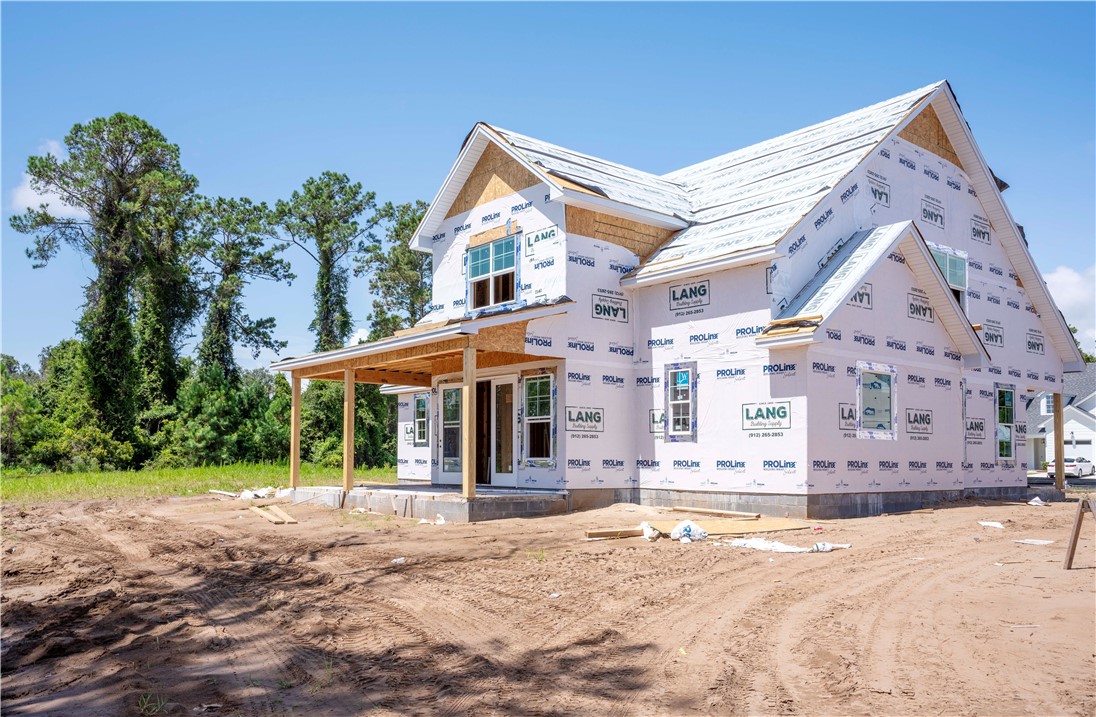 Two-story house under construction with a covered porch and building wrap.