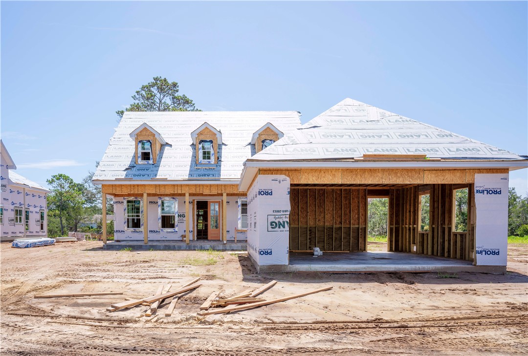 Two-story house under construction with three front dormers and an unfinished open garage.