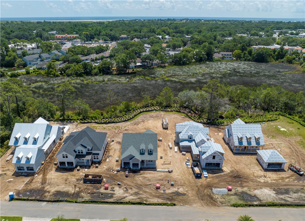 Aerial view of houses under construction beside a wooded marsh.