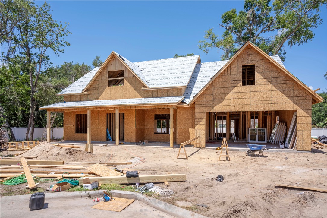 Two-story home under construction with multiple gables and exposed wood sheathing.