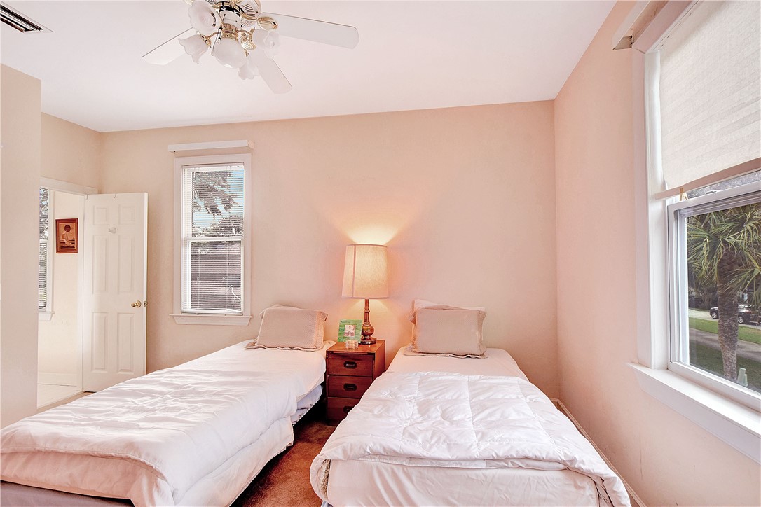 Bedroom with two twin beds, white bedding, and a shared bedside table between the beds.