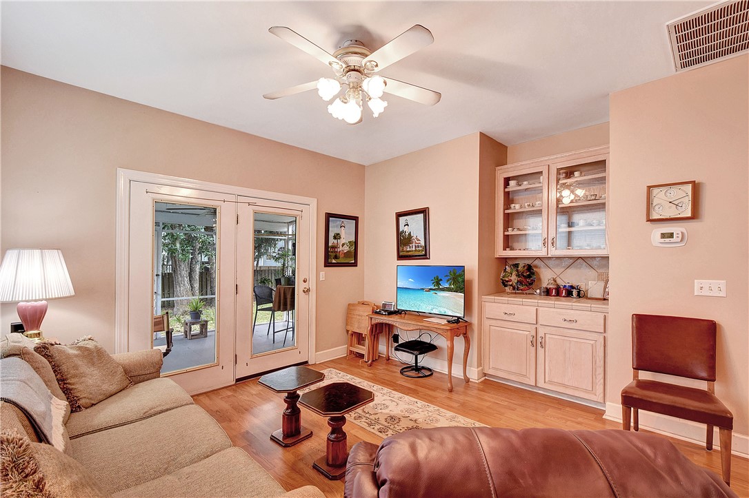 Living room with French doors opening to a garden, built-in cabinets, and beige sofas.