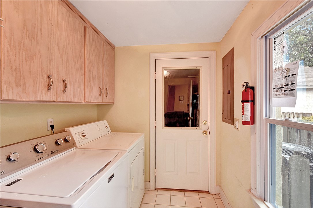 Laundry room with white washer and dryer, pale wood cabinets, and a windowed door.