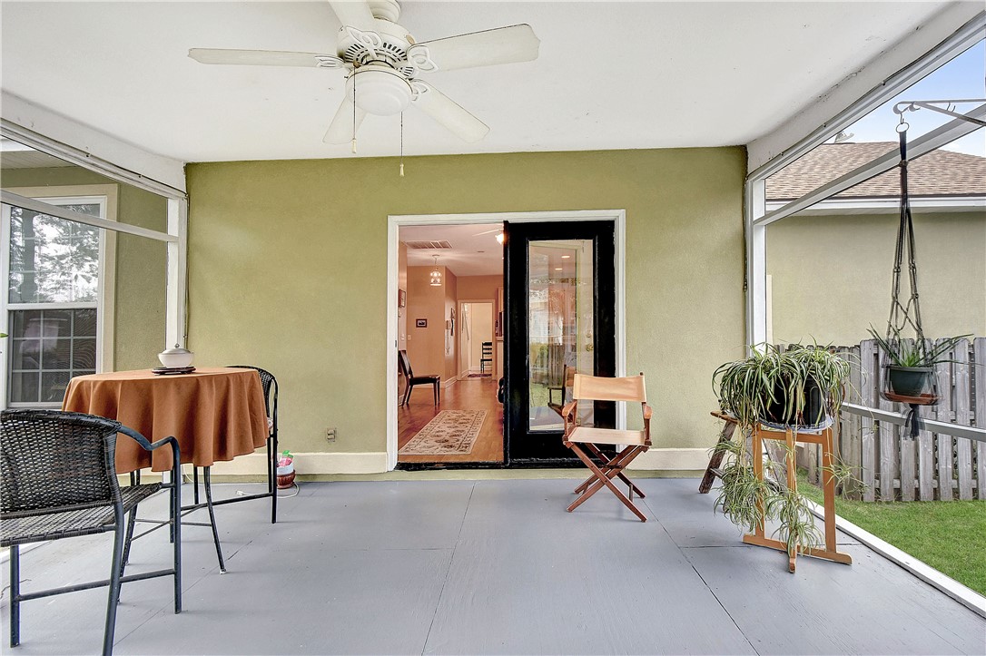 Covered patio with seating, a ceiling fan, and sliding doors opening into the home.