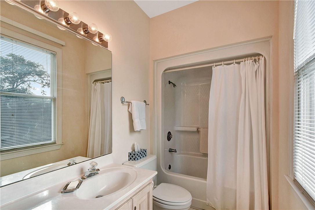 Bathroom with a white vanity, large mirror, and tub-shower with a white curtain.
