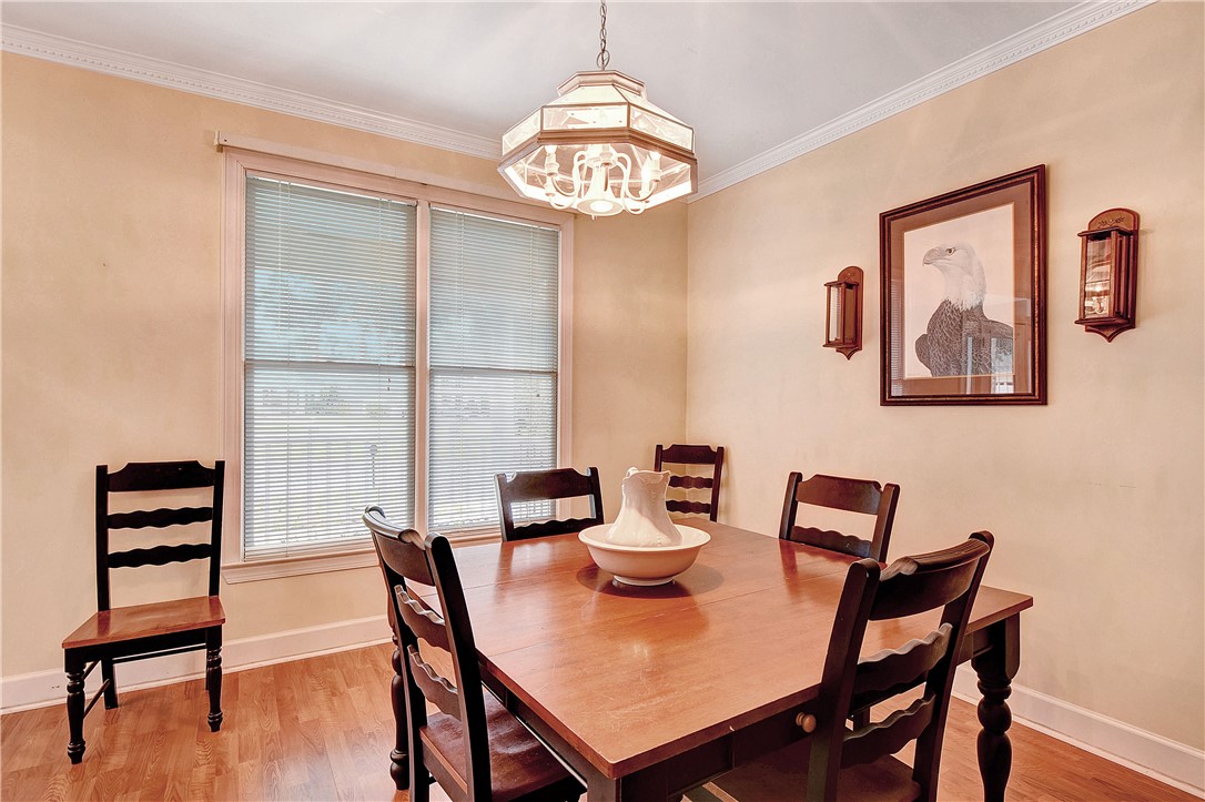 Dining room with a wooden table, dark chairs, chandelier, and framed eagle artwork.
