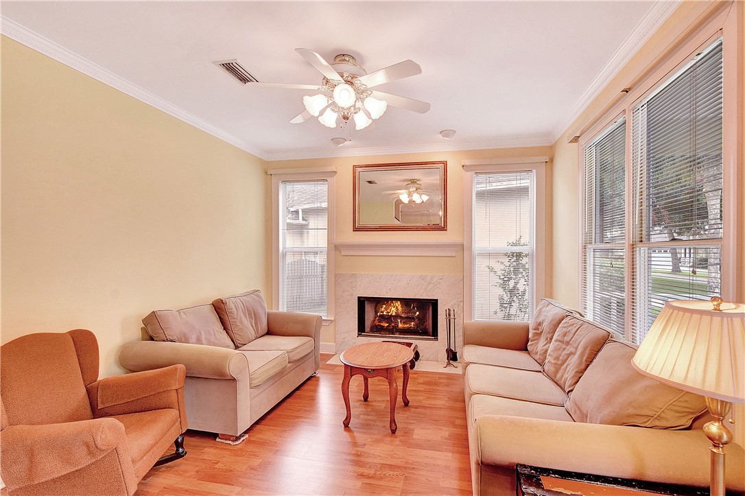Living room with a fireplace, cream sofas, and tall windows with blinds.