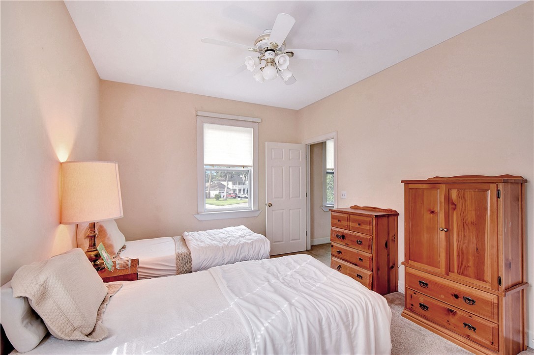Bedroom with two beds, pale pink walls, and wooden dressers and wardrobe.