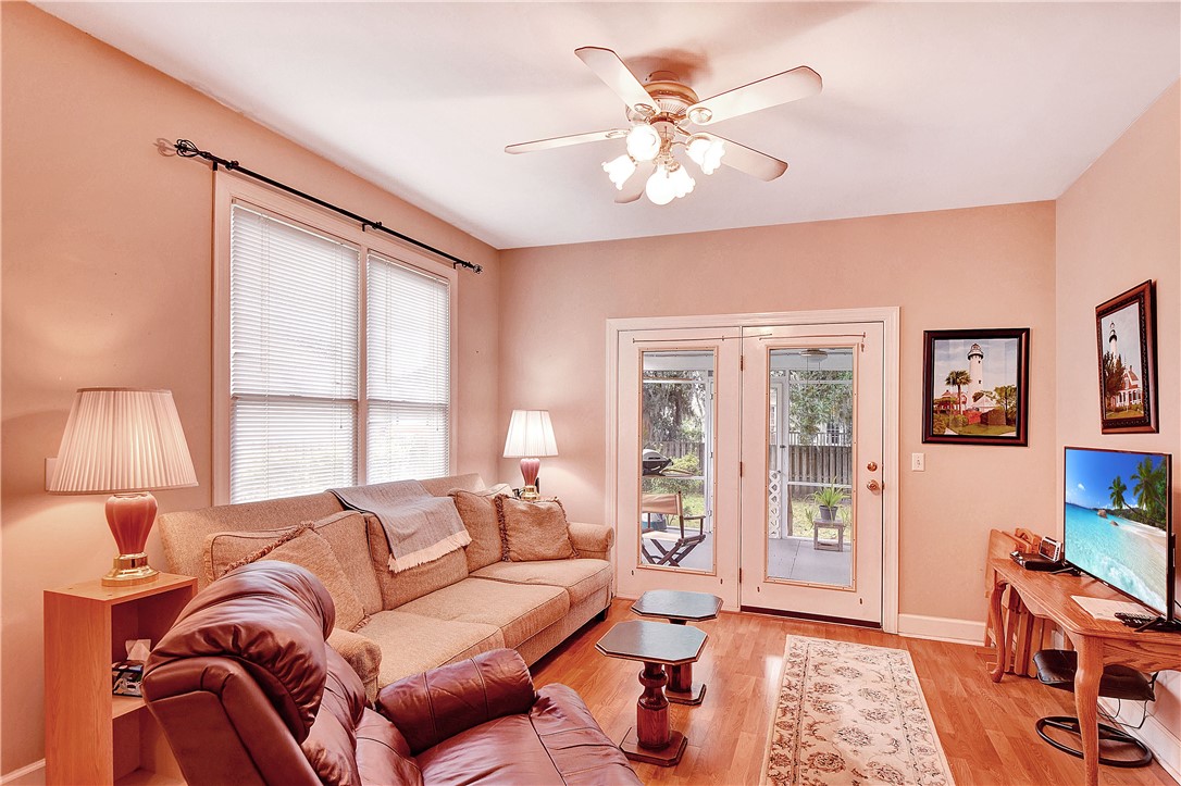 Living room with beige sofa, leather recliner, and glass doors opening to a fenced outdoor area.